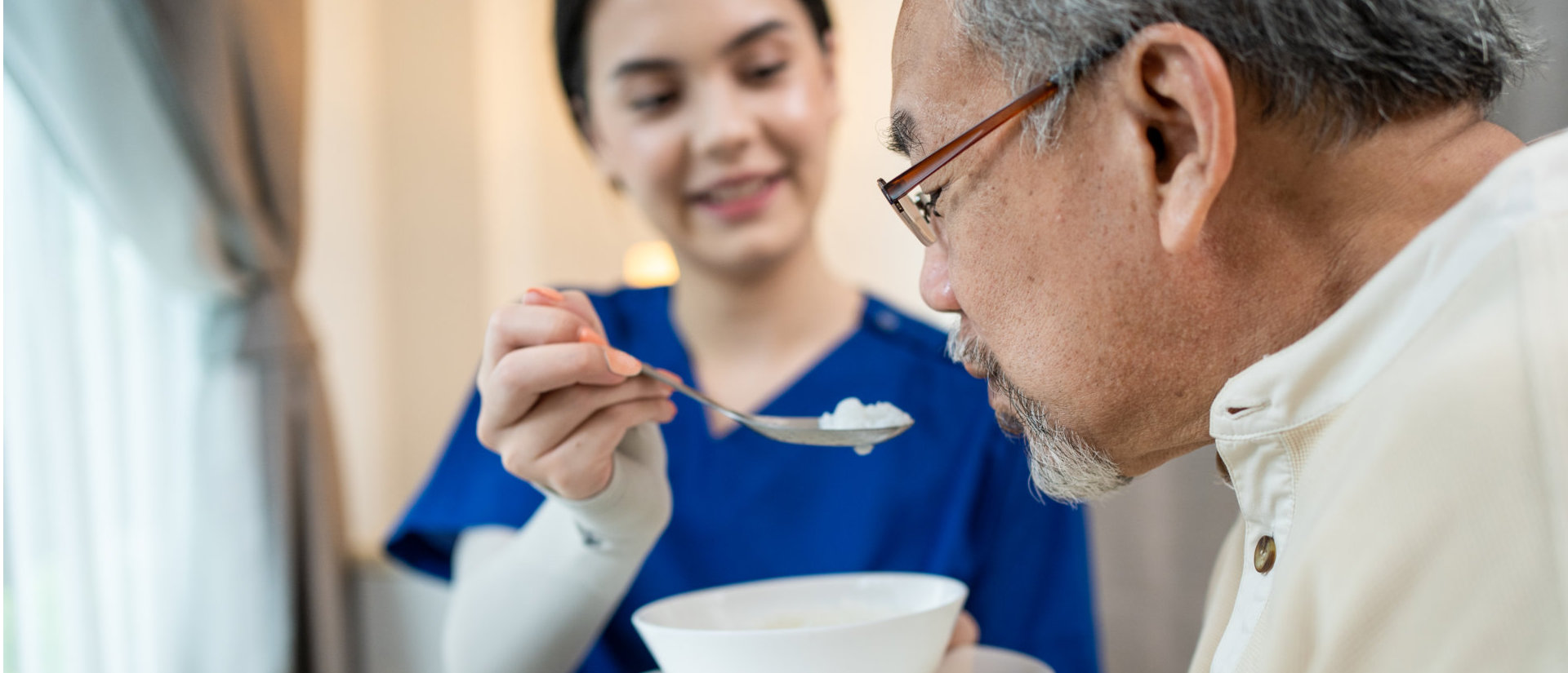 image of a female caregiver feeding an elderly man